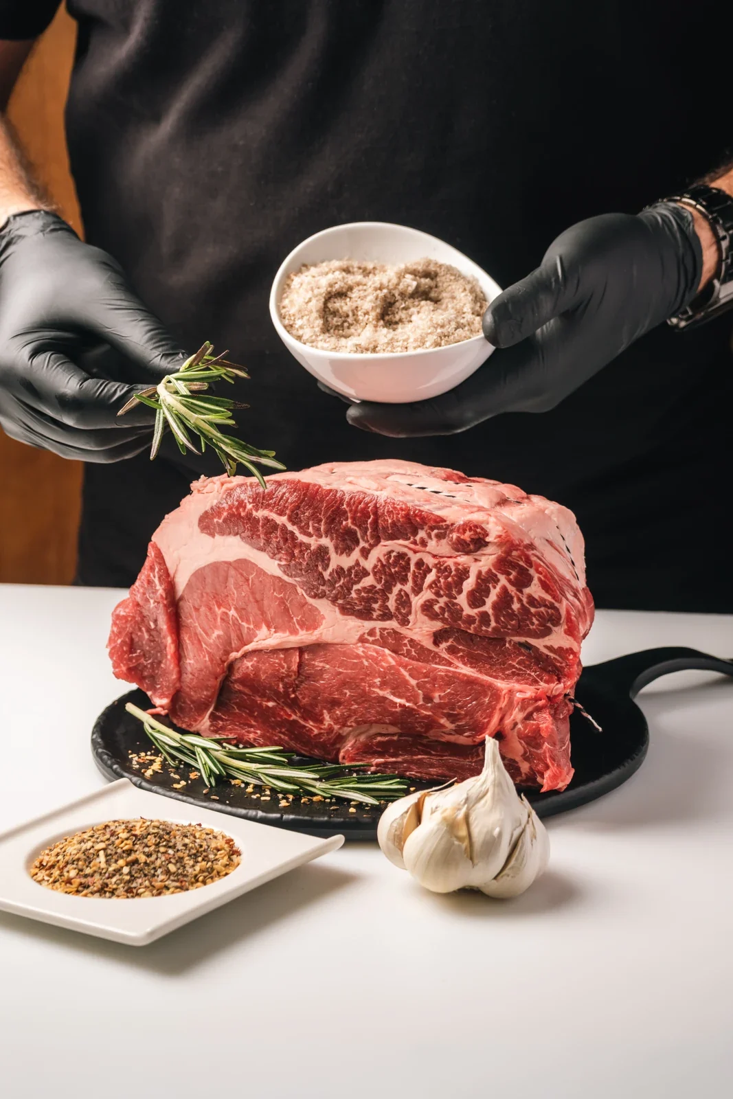 A butcher in Teodora’s apron preparing a roast with rosemary and seasoning